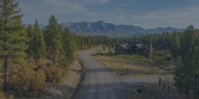 A beautiful, well-maintained gravel road leading through a pine forest toward a luxury mountain home in Pagosa Springs.